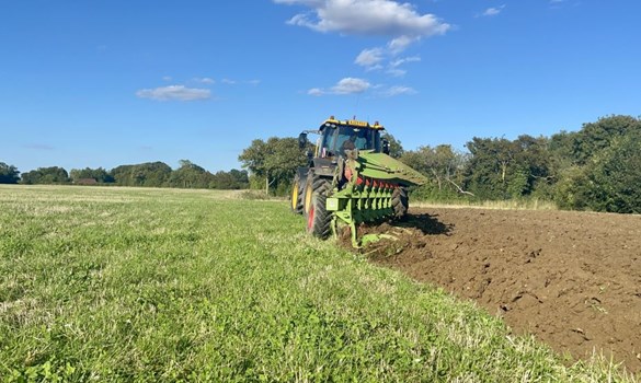 Green tractor ploughing a field.